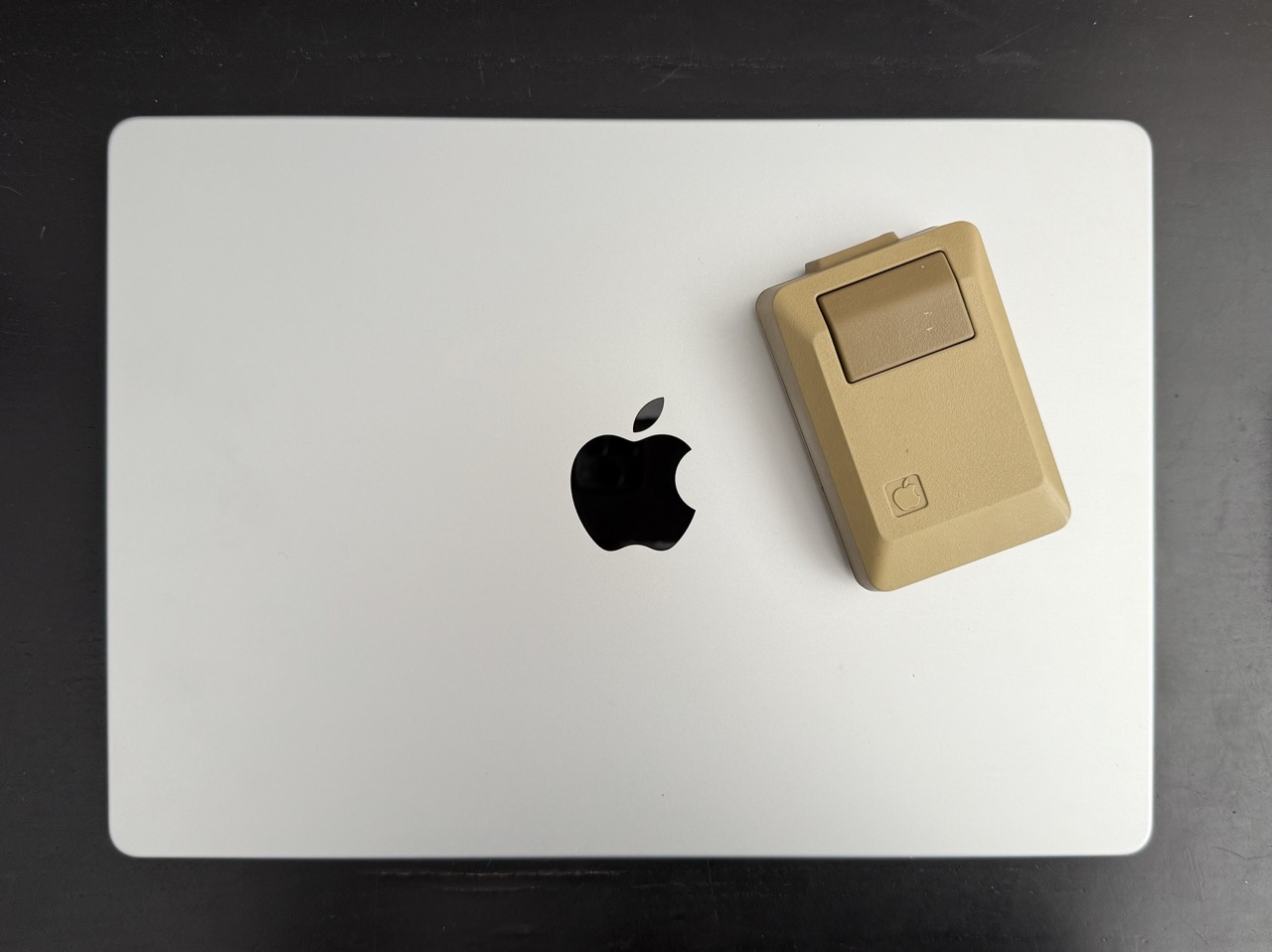 A 1985 Apple Mouse sitting on top of a 2025 Macbook Pro